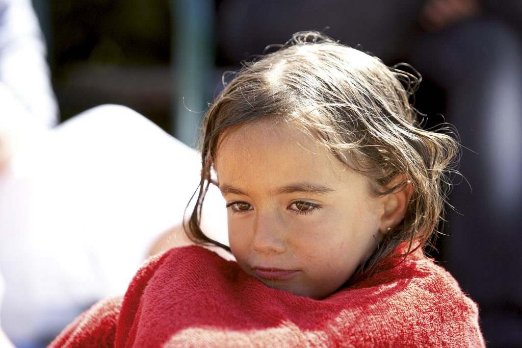 Ein Mädchen in eine Decke gehüllt als Symbol für Kinderarmut